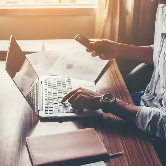 male using laptop and phone calculating