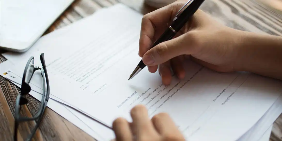 glasses on paper while hand signing paper